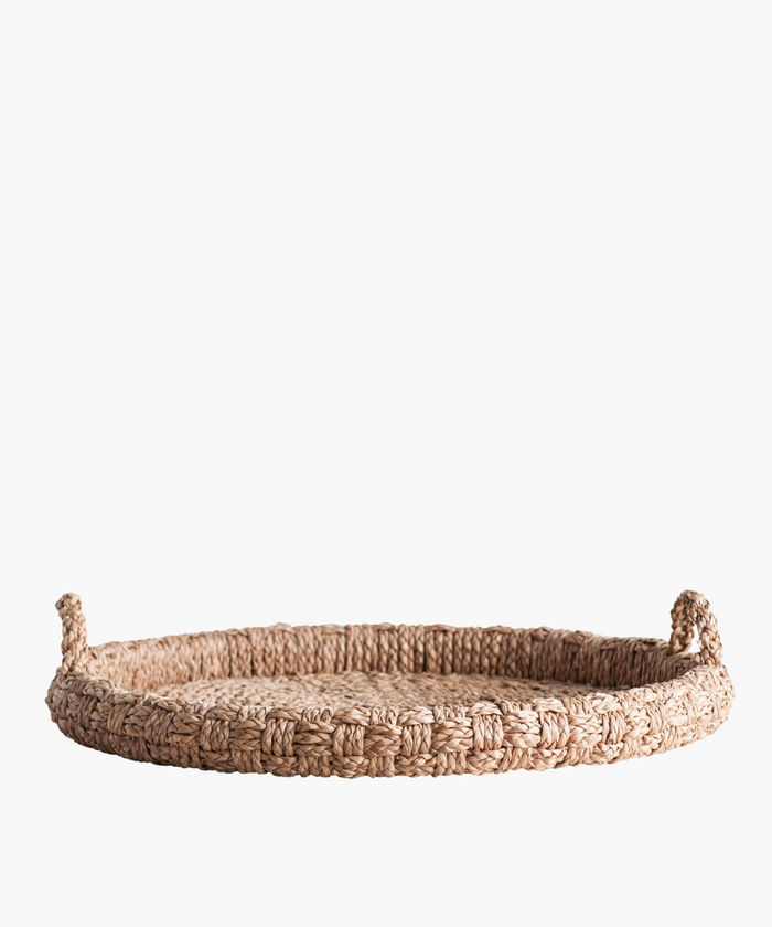 Round braided wicker tray or basket with two looped handles. The natural fibers create a warm, rustic feel. The basket's texture is tightly knit and sturdy. | SW Home