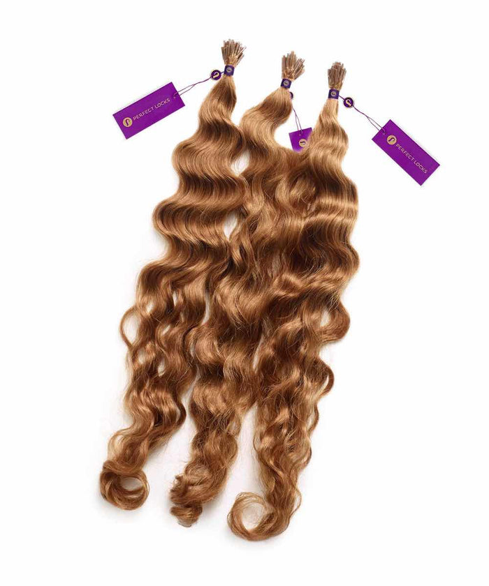 Three bundles of wavy, light brown human hair extensions with purple tags attached, laid out on a white background.