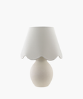 A cream-colored table lamp with a rounded base and a scalloped fabric shade, conveying a cozy and elegant feel. The design is minimalist and classic. | Wildwood Home Co.