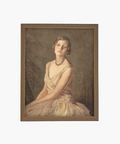Portrait of a woman in a soft yellow dress and necklace, seated against a soft, muted background. Her expression is serene and contemplative. Framed in gold. | Wildwood Home Co.