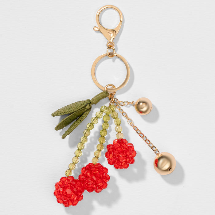 Cute cherry handbag charm with glossy bead cherries, textured fringe and metallic accents